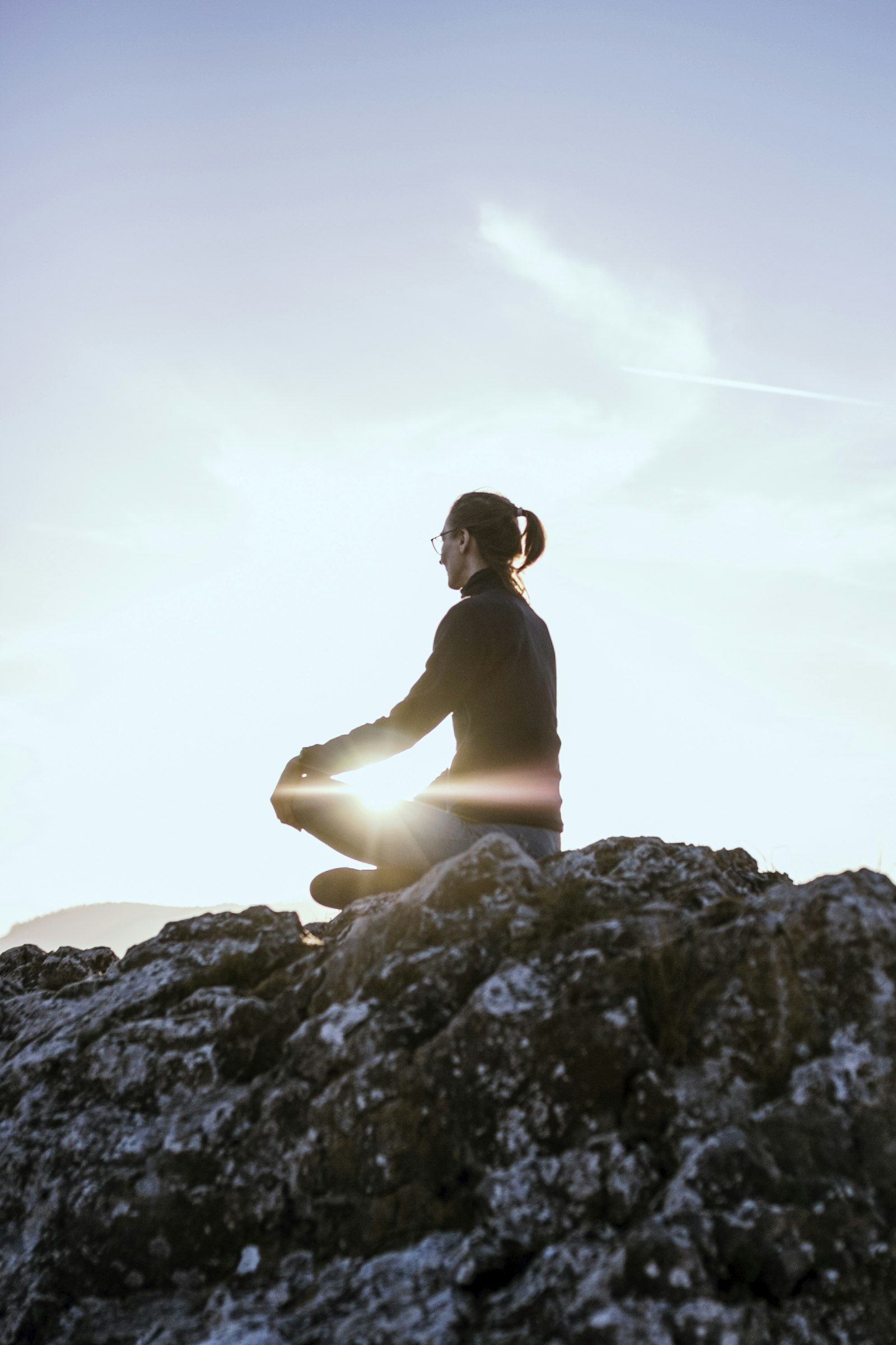 Person meditating on a rock outdoors