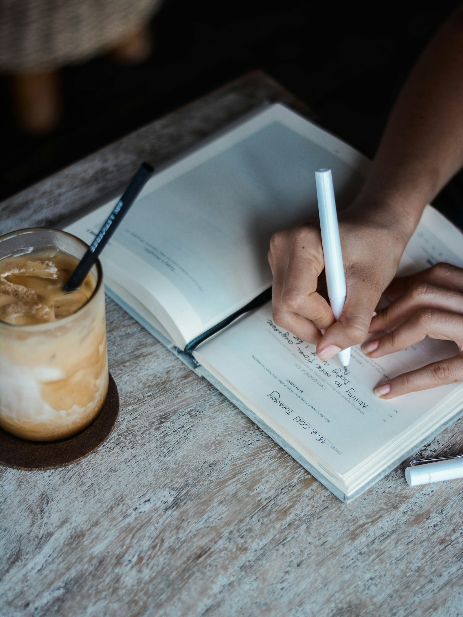 Writing in a journal beside an iced coffee