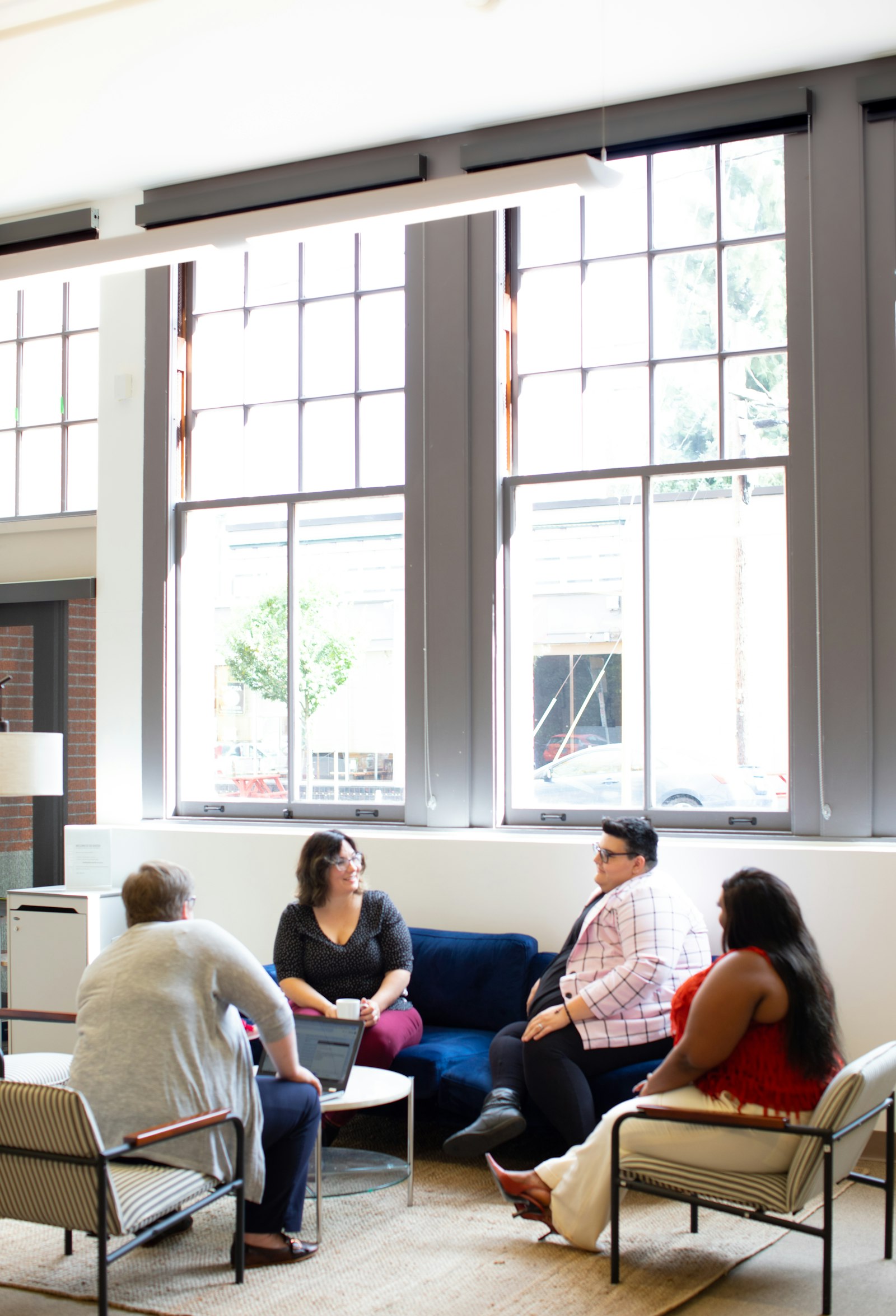Small group sitting together by large windows