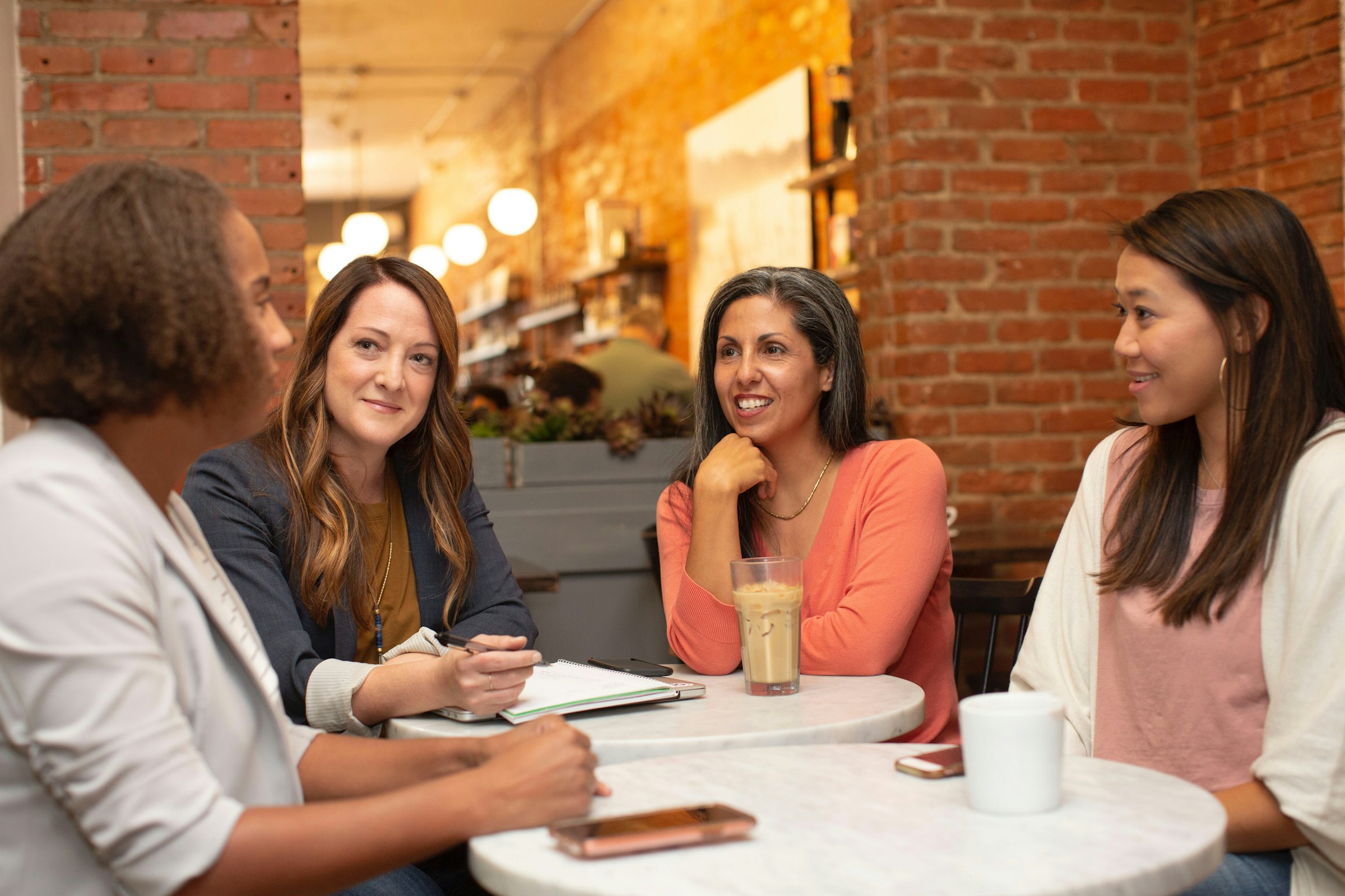 Four women talking together at a cafe table