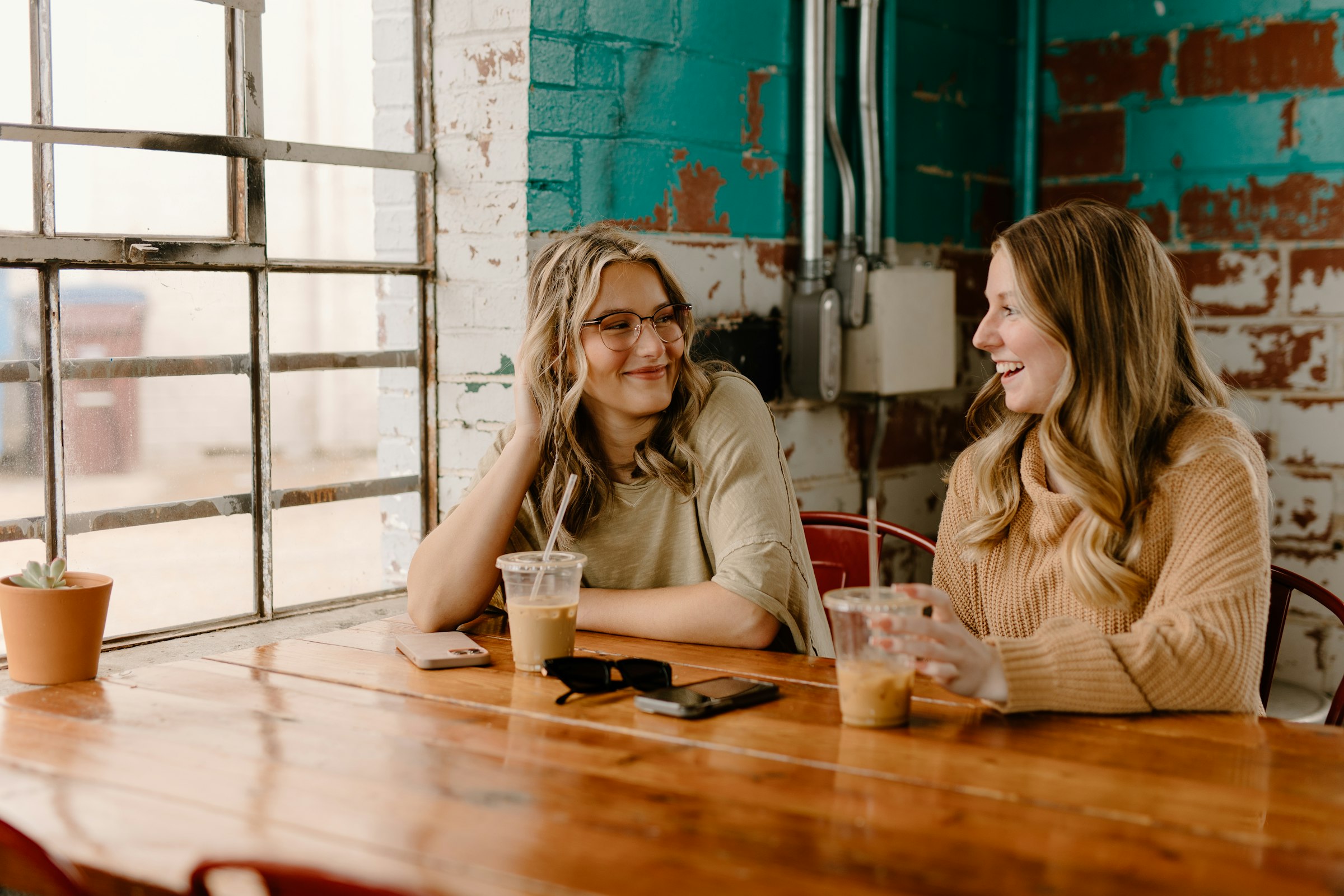 Two women talking and laughing at a cafe table