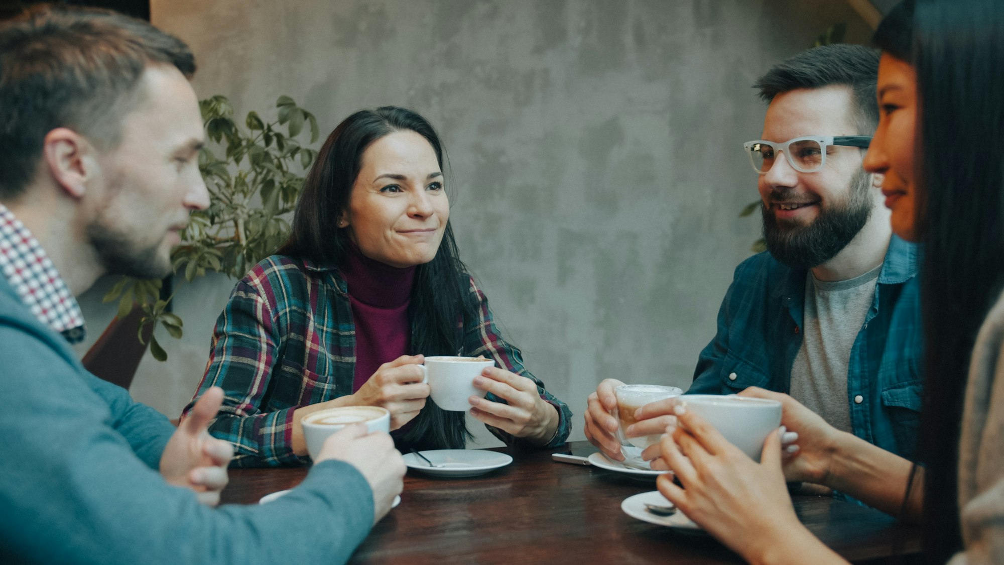 Four people talking over coffee at a wooden table
